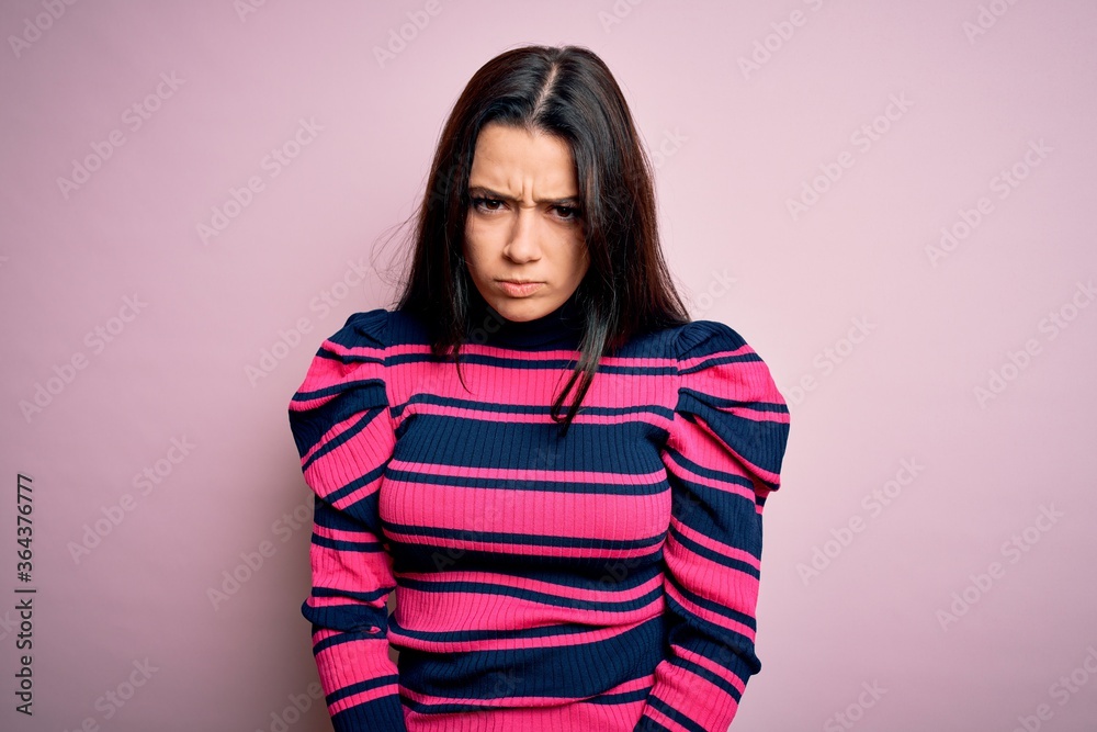 Young brunette elegant woman wearing striped shirt over pink isolated background skeptic and nervous, frowning upset because of problem. Negative person. Young brunette elegant woman wearing striped shirt over pink isolated background skeptic and nervous, frowning upset because of problem. Negative person.