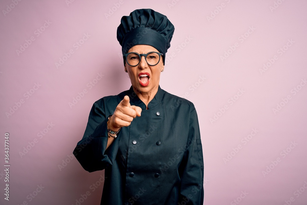 Middle age brunette chef woman wearing cooker uniform and hat over isolated pink background pointing displeased and frustrated to the camera, angry and furious with you Middle age brunette chef woman wearing cooker uniform and hat over isolated pink background pointing displeased and frustrated to the camera, angry and furious with you