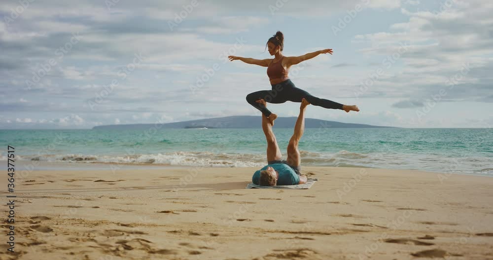 Amazing fitness couple practicing acro yoga on the beach, health and wellness lifestyle Amazing fitness couple practicing acro yoga on the beach, health and wellness lifestyle