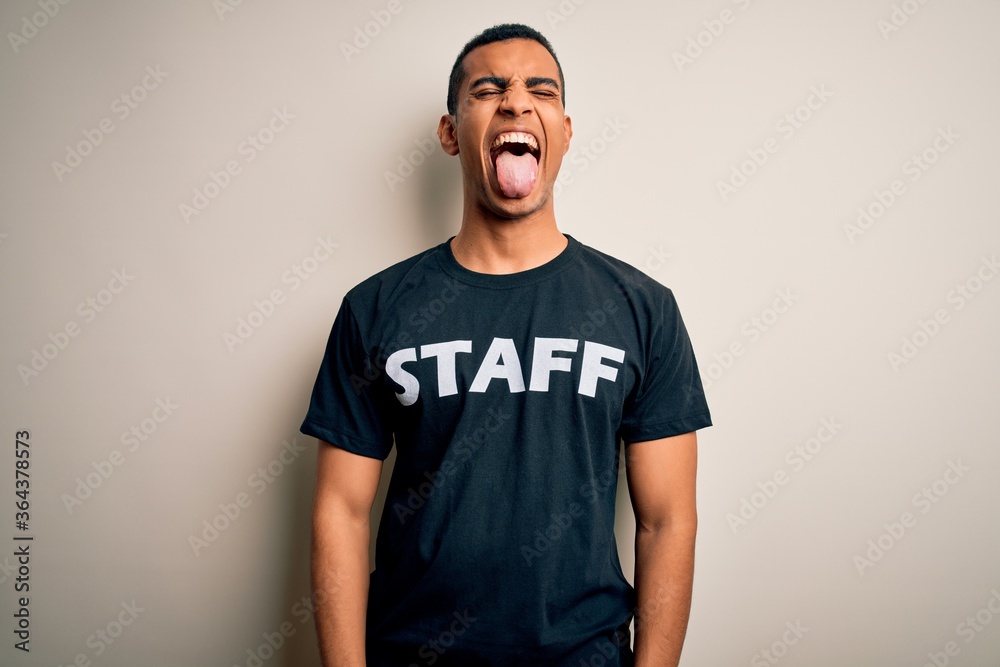 Young handsome african american worker man wearing staff uniform over white background sticking tongue out happy with funny expression. Emotion concept. Young handsome african american worker man wearing staff uniform over white background sticking tongue out happy with funny expression. Emotion concept.