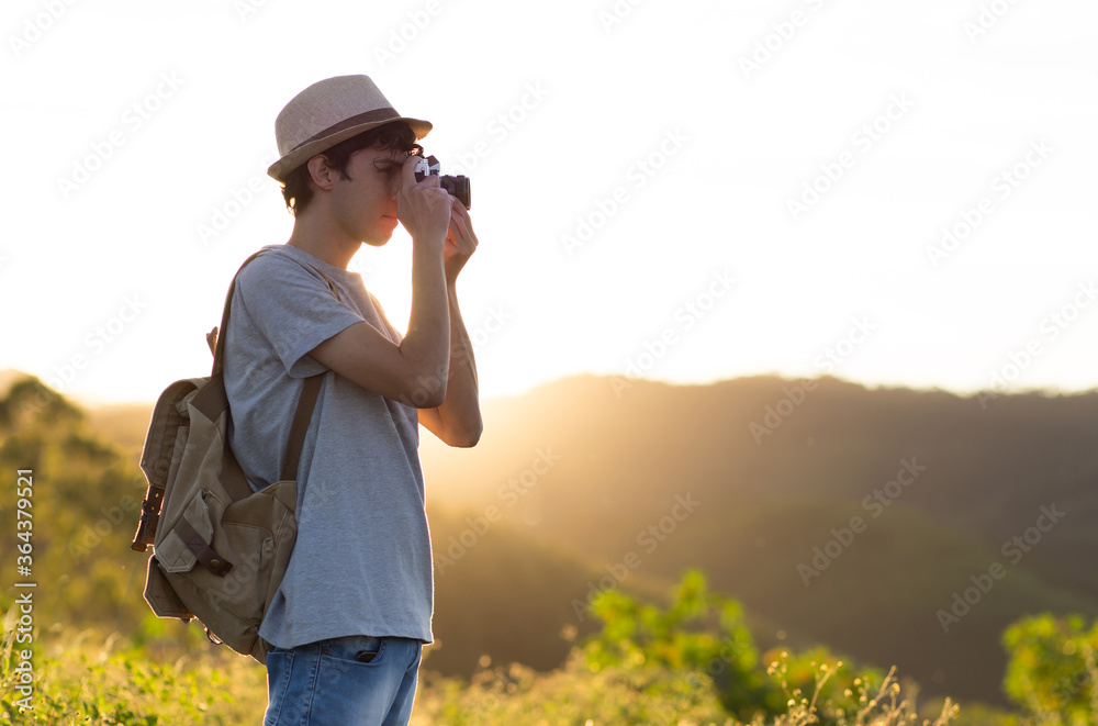 Tourist, backpacker or photographer taking photographs with his camera, with sunset in the background Tourist, backpacker or photographer taking photographs with his camera, with sunset in the background