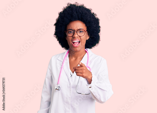 Young african american woman wearing doctor coat and stethoscope pointing displeased and frustrated to the camera, angry and furious with you