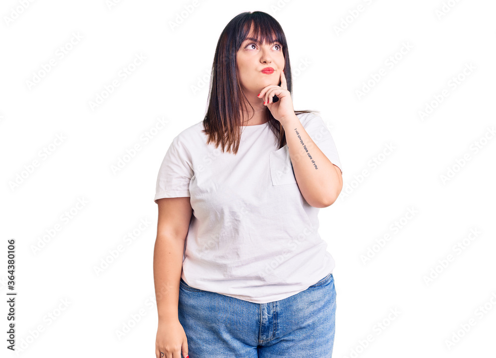 Young plus size woman wearing casual clothes with hand on chin thinking about question, pensive expression. smiling and thoughtful face. doubt concept. Young plus size woman wearing casual clothes with hand on chin thinking about question, pensive expression. smiling and thoughtful face. doubt concept.