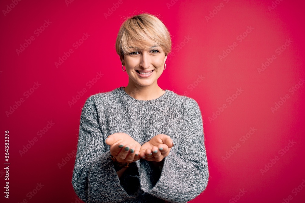 Young blonde woman with modern short hair wearing casual sweater over pink background Smiling with hands palms together receiving or giving gesture. Hold and protection Young blonde woman with modern short hair wearing casual sweater over pink background Smiling with hands palms together receiving or giving gesture. Hold and protection