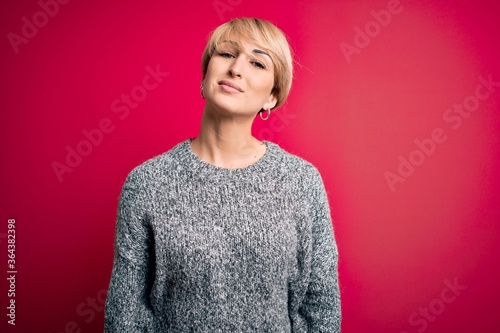 Young blonde woman with modern short hair wearing casual sweater over pink background looking sleepy and tired, exhausted for fatigue and hangover, lazy eyes in the morning.