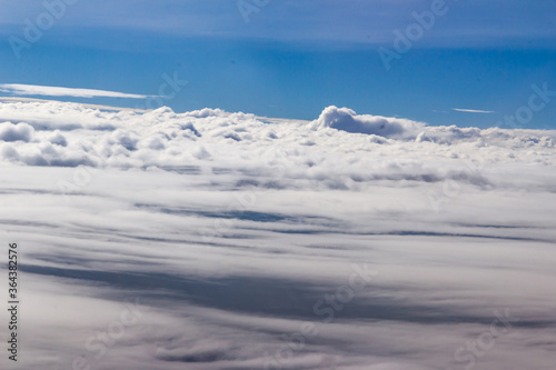 Beautiful cloudscape and blue sky from aerial view, nature view from above the sky and clouds. White clouds and blue sky view like the heaven from airplane window. Sunlight in the sky shines on clouds © kampwit