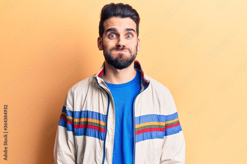Young handsome man with beard wearing casual jacket puffing cheeks with funny face. mouth inflated with air, crazy expression. Young handsome man with beard wearing casual jacket puffing cheeks with funny face. mouth inflated with air, crazy expression.