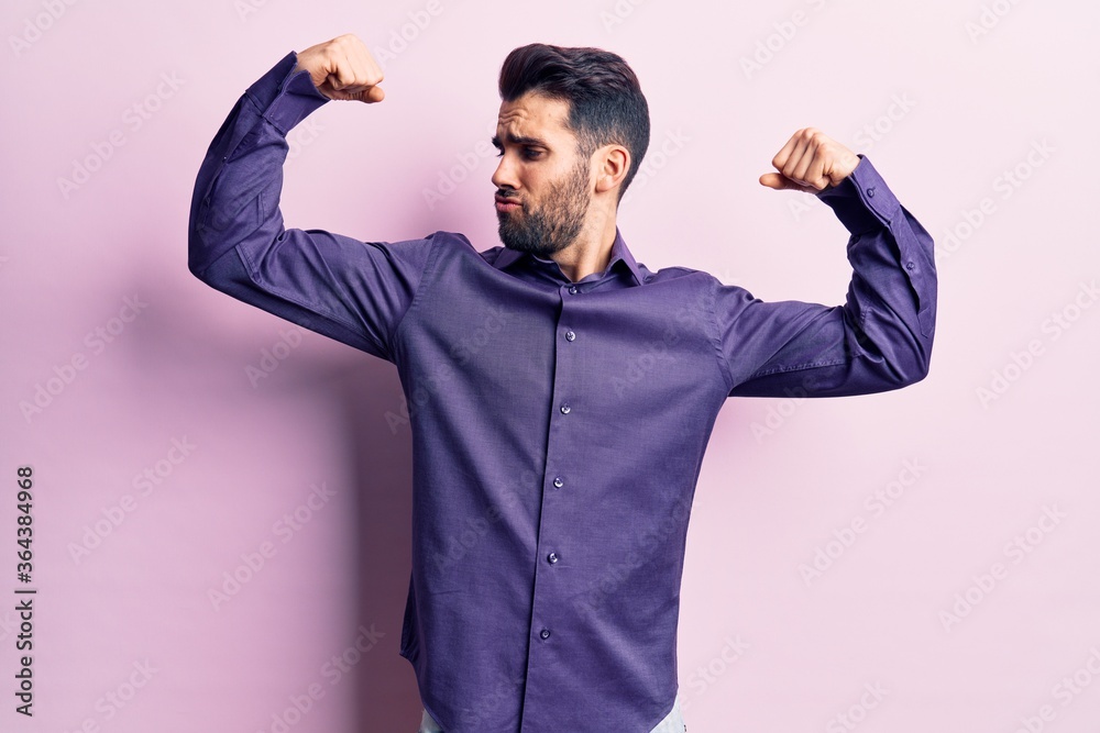Young handsome man with beard wearing casual shirt showing arms muscles smiling proud. fitness concept. Young handsome man with beard wearing casual shirt showing arms muscles smiling proud. fitness concept.