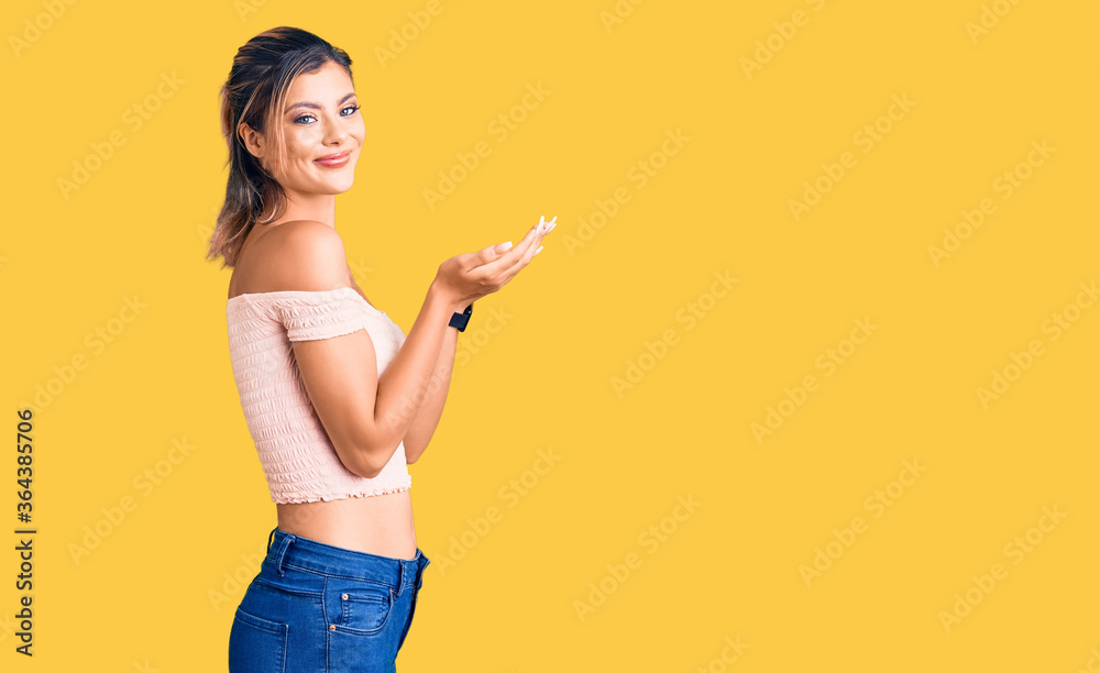 Young beautiful woman wearing casual clothes pointing aside with hands open palms showing copy space, presenting advertisement smiling excited happy Young beautiful woman wearing casual clothes pointing aside with hands open palms showing copy space, presenting advertisement smiling excited happy