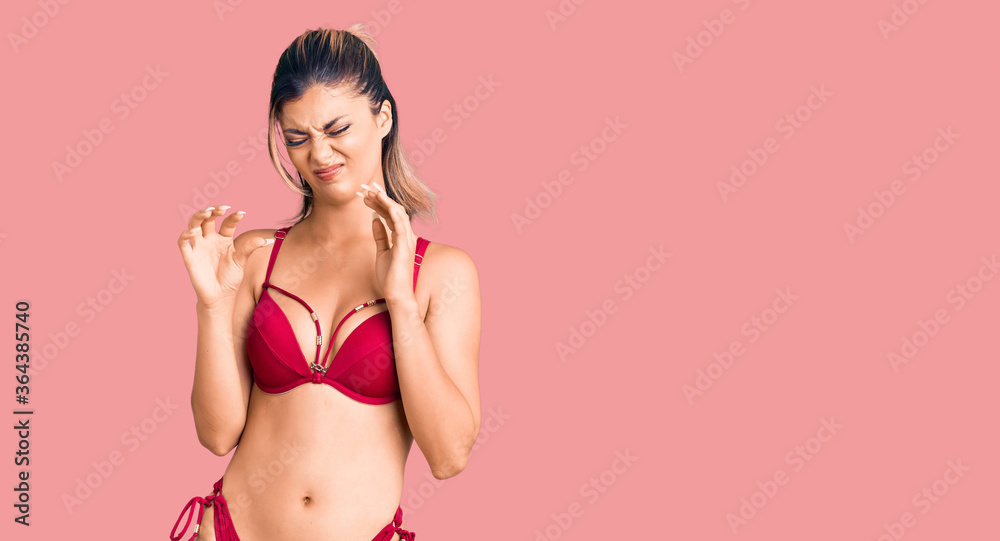 Naklejka premium Young beautiful woman wearing bikini disgusted expression, displeased and fearful doing disgust face because aversion reaction.
