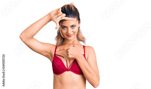 Young beautiful woman wearing bikini smiling making frame with hands and fingers with happy face. creativity and photography concept.