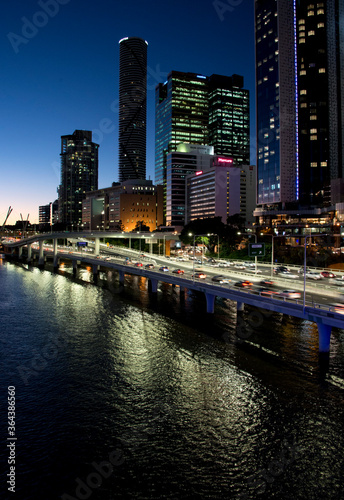 Brisbane Australia at night with the Brisbane river in the foreground and the city skyline and traffic in the background 