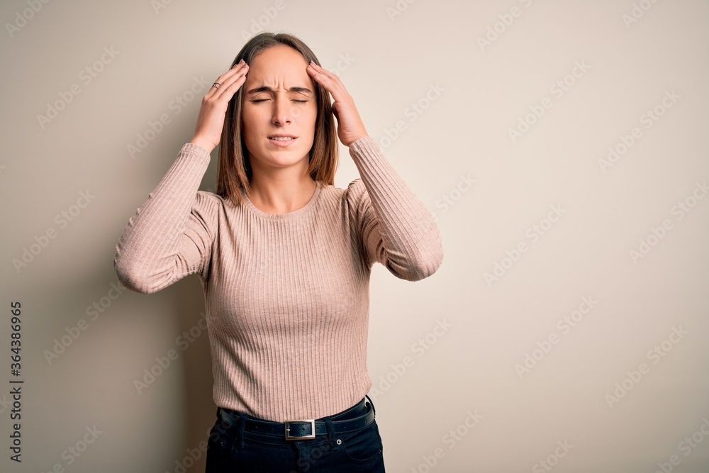 Young beautiful woman wearing casual sweater standing over isolated white background with hand on head for pain in head because stress. Suffering migraine. Young beautiful woman wearing casual sweater standing over isolated white background with hand on head for pain in head because stress. Suffering migraine.