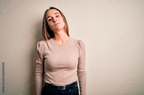 Young beautiful woman wearing casual sweater standing over isolated white background Relaxed with serious expression on face. Simple and natural looking at the camera.