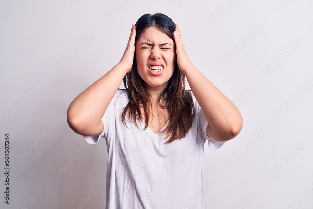 Young beautiful brunette woman wearing casual t-shirt standing over isolated white background with hand on head, headache because stress. Suffering migraine. Young beautiful brunette woman wearing casual t-shirt standing over isolated white background with hand on head, headache because stress. Suffering migraine.