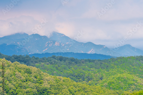 Landscape of forested mountain region with clouds over mountains