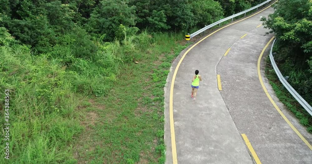 Aerial view of fitness woman runner running on mountain top trail 