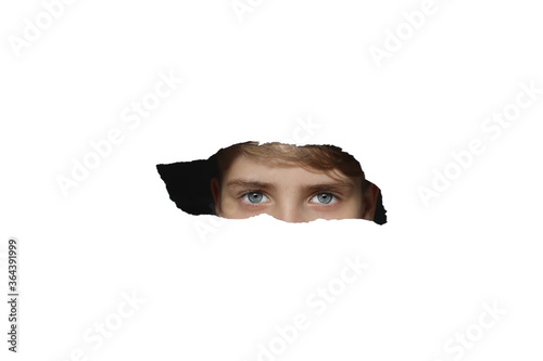 Boy looking through a hole on paper. White isolated. Blue eyes. © Aleksandr