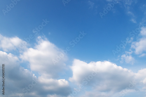 Beautiful natural sunny blue sky background with cotton candy white cumulus clouds & puffy fluffy cloudscape in tropical summer or spring sunlight & sun rays on bright daylight horizon at sunshine day
