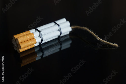 Cigarettes are twisted into a dynamite checker with a filament on a black reflective surface.