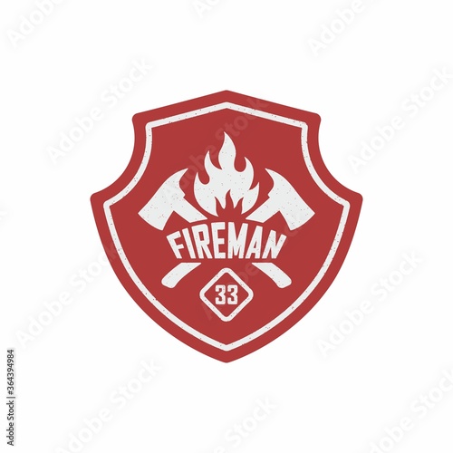 Color illustration of a red shield, text, crossed axes, fire on a white background. Vector illustration of a firefighter logo in vintage style with grunge texture.