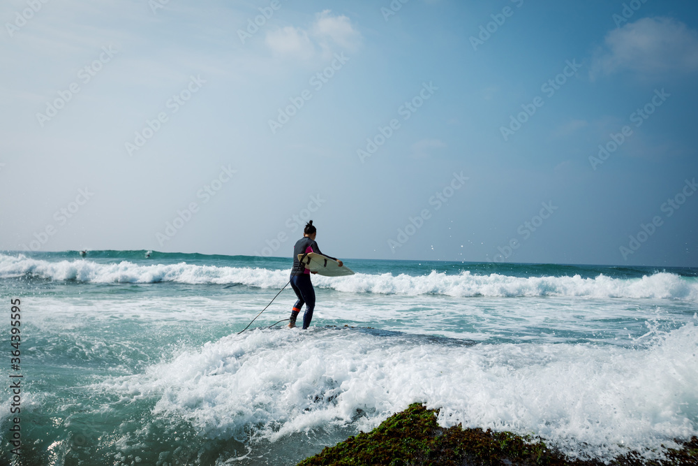 Woman surfer with surfboard going to surf on seaside Woman surfer with surfboard going to surf on seaside