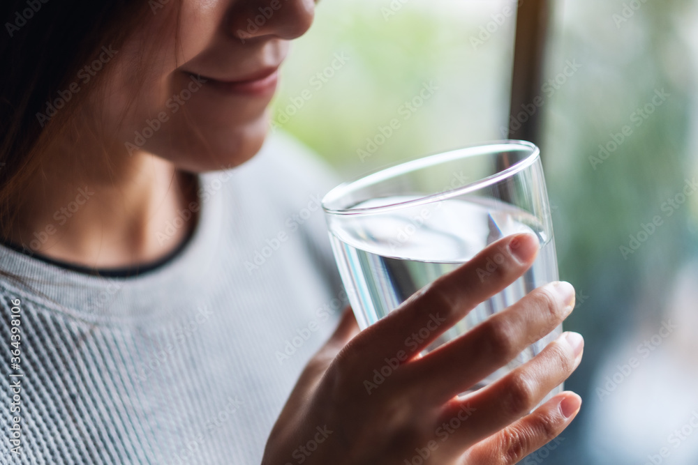 Closeup image of a beautiful young asian woman holding a glass of water to drink Closeup image of a beautiful young asian woman holding a glass of water to drink