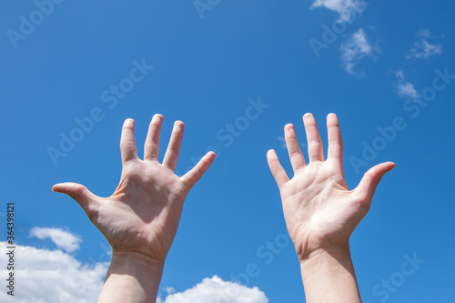 Close-up of female hands, empty open palms on a background of blue sky. Number ten in sign language. Copy space