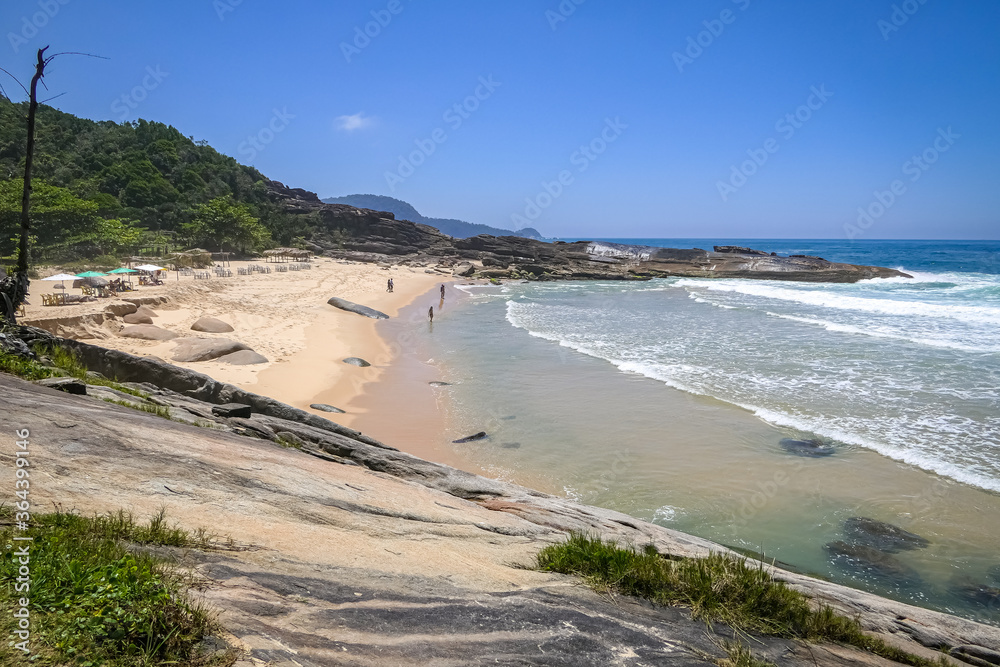 View along mountainous coastline with sandy beach and rock slabs, Picinguaba, Brazil
