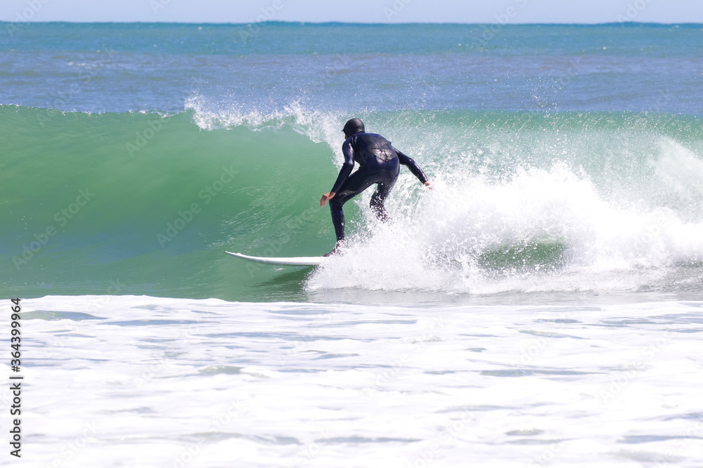 Japan surfing , sometimes during a typhoon, there are many waves in Japan especially in Hebara, Katsuura, Chiba. Westerner surfs large waves. Sunrise & at the beach with a surfer & his surf board.