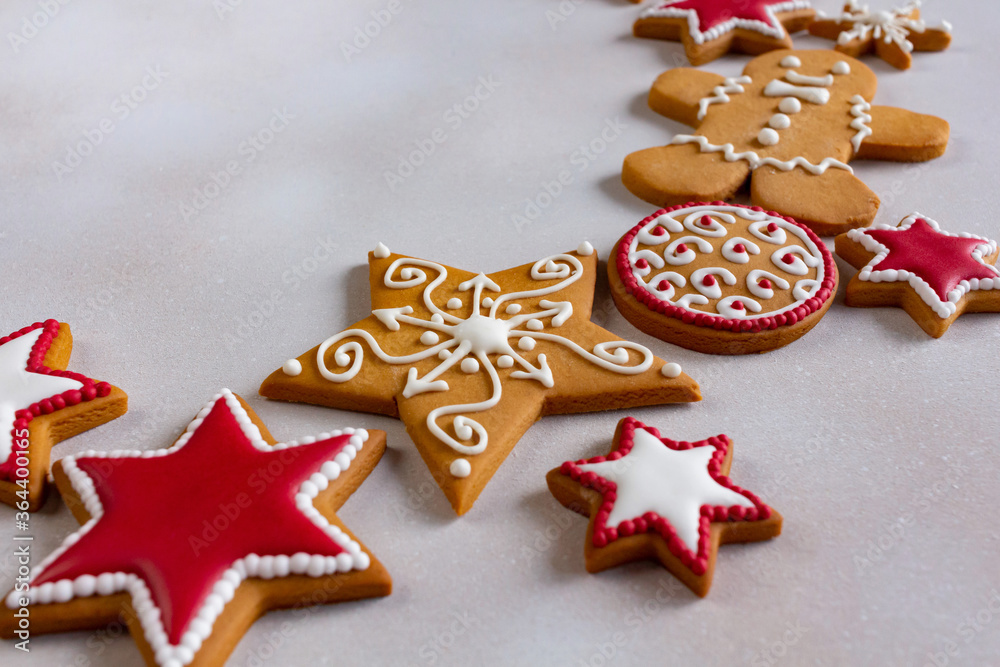 Closeup of gingerbread cookies on white snow background with copy space. Glazed painted cookies: snowflakes, stars, gingerbread man, balls. Christmas and New Year decoration and greetings consept.