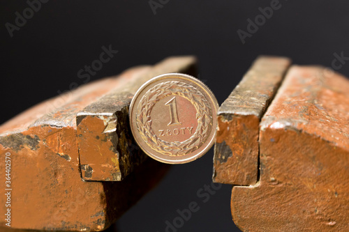1 zloty coin in a metal vise. Concept of economic problems. Selective focus. Close up.