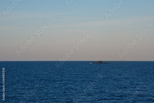 The submarine is surfaced in the open sea in the early morning. Seascape. Clear sky over the dark blue sea.