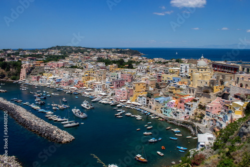 Panoramic view of the beautiful Procida in sunny summer day. Colored houses in Marina Corricella, clear blue sky and blue sea.