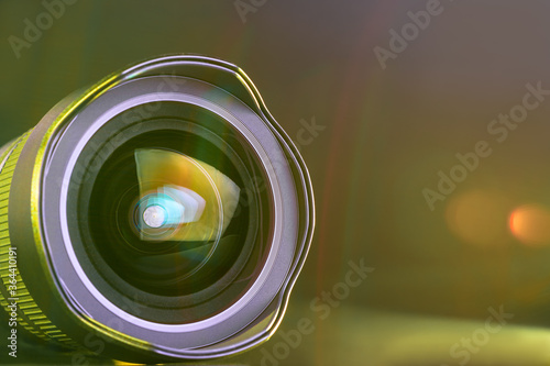 ..The camera lens with gold light. Close-up of the camera lens on a black background with gold illumination. Optics.