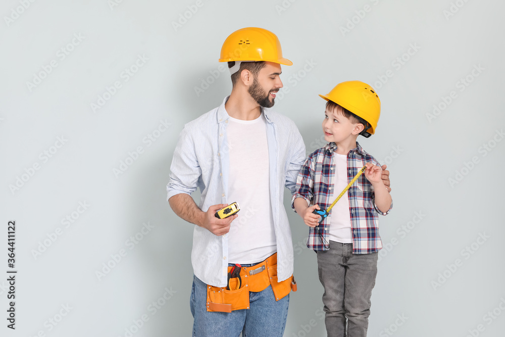 Father and son with measuring tapes on grey background Father and son with measuring tapes on grey background