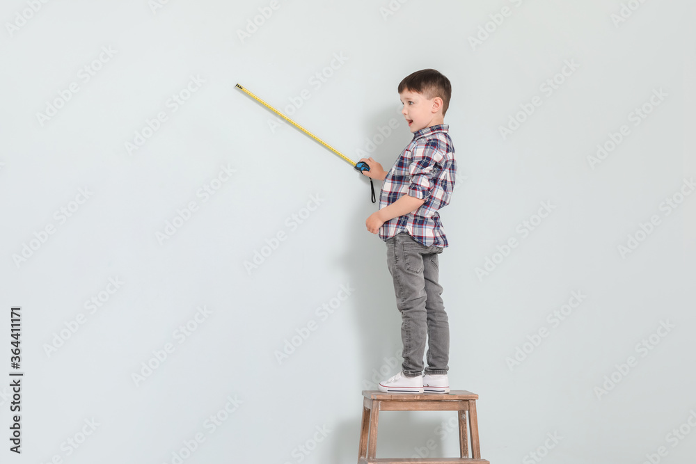 Little boy with measuring tape on grey background Little boy with measuring tape on grey background