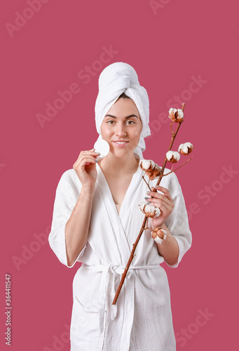 Beautiful young woman with cotton flowers and cosmetic pad on color background © Pixel-Shot