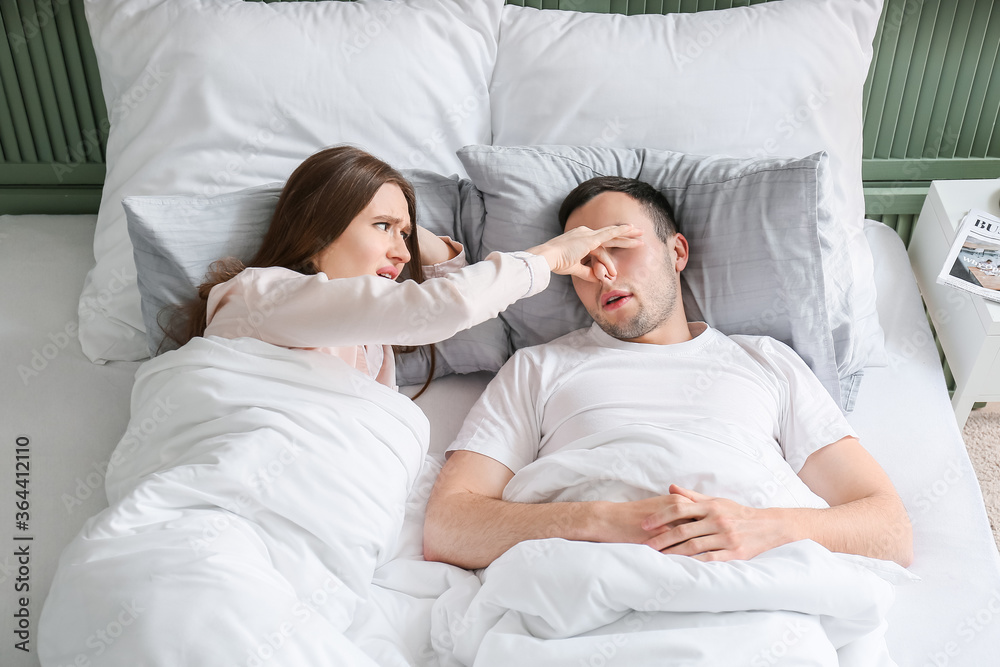 Young irritated woman in bed with snoring husband Young irritated woman in bed with snoring husband