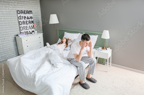 Young irritated man in bed ...