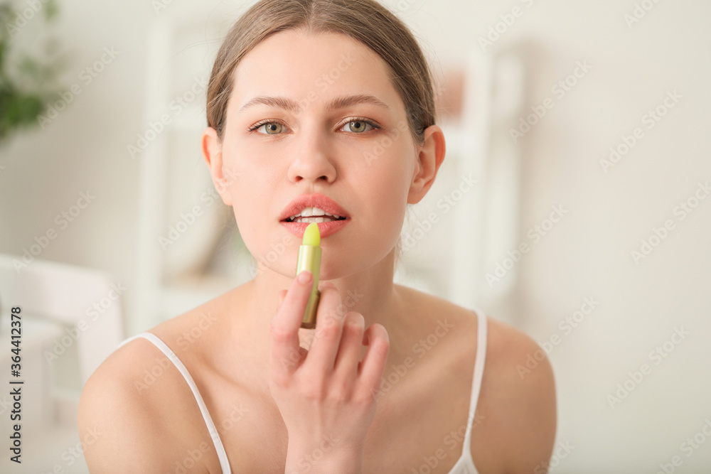 Beautiful young woman with lip balm at home Beautiful young woman with lip balm at home
