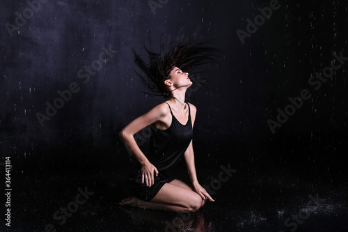 Beautiful young woman and dripping water on dark background