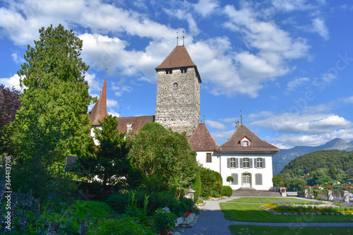 A monument of architecture, the medieval castle in Spiez, Switzerland. Green garden for walking, summer Sunny weather, blue sky, green grass.