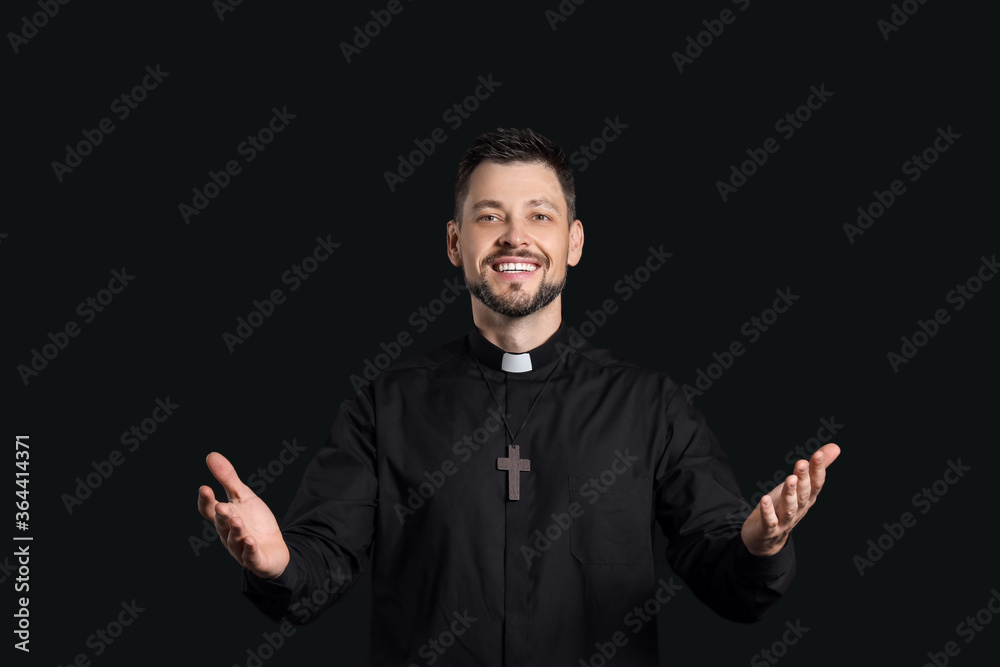 Handsome priest on dark background