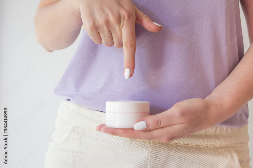 A jar of anti-aging cream is held in the hands of a woman with a beautiful manicure. Natural organic eco-friendly cosmetics for skin rejuvenation A jar of anti-aging cream is held in the hands of a woman with a beautiful manicure. Natural organic eco-friendly cosmetics for skin rejuvenation