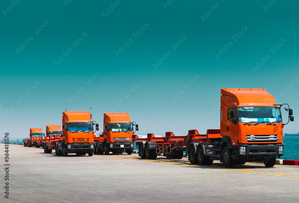 Fleet of trucks and trailer awaiting to pick containers on jetty harbor. Container transportation and logistics, trucking and delivery. Fleet of trucks and trailer awaiting to pick containers on jetty harbor. Container transportation and logistics, trucking and delivery.