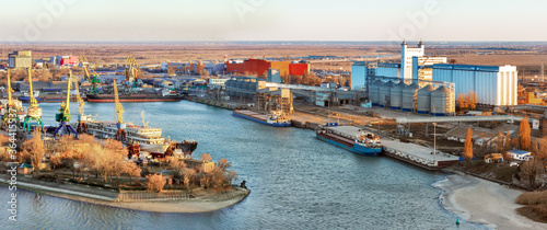 The panoramic view the river harbor with the big industrial building of grain elevator and a cargo berth for loading grain onto bulk-carriers. International wheat trade