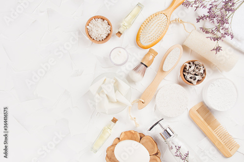 Elegant beige natural cosmetic products and accessories with lavender twigs for body and skin care on soft light white background, top view, copy space.
