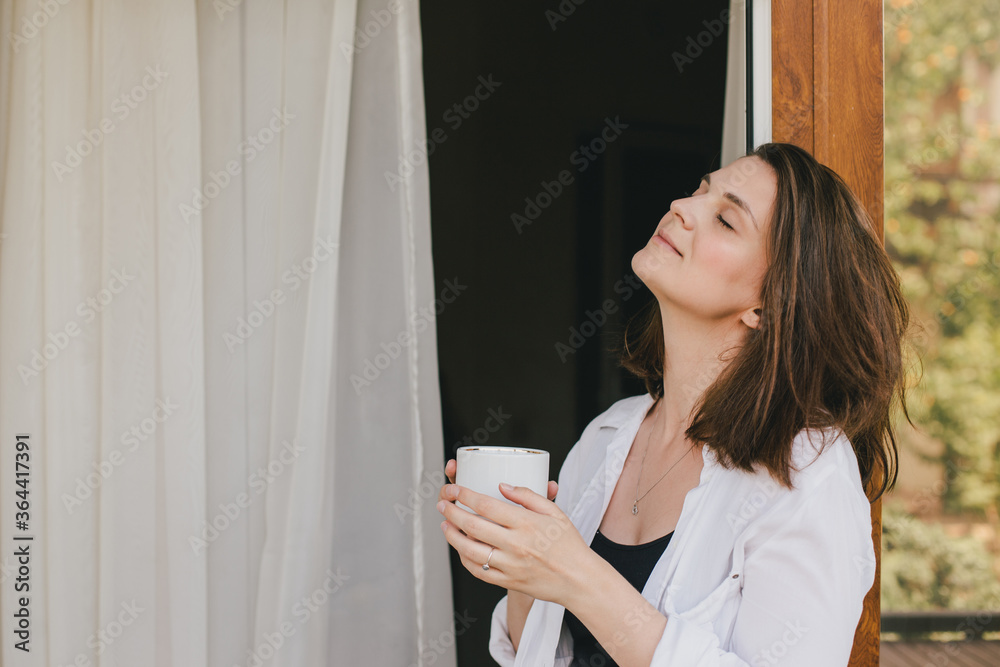 Young beautiful woman drinking tea on cozy terrace of a wooden country house. Young beautiful woman drinking tea on cozy terrace of a wooden country house.