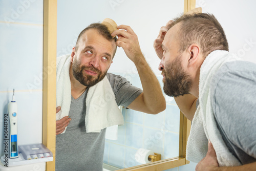 Man using comb in bathroom